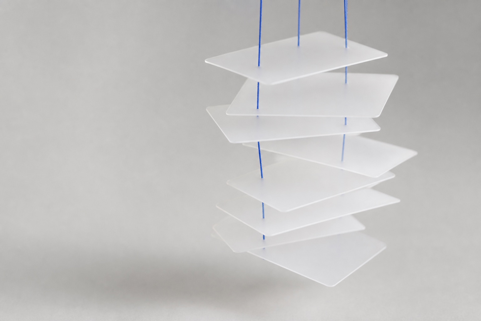 Frosted index cards suspended on thin blue threads