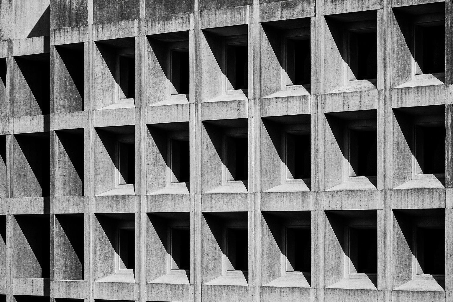 A brutalist concrete facade with a strict grid of recessed windows