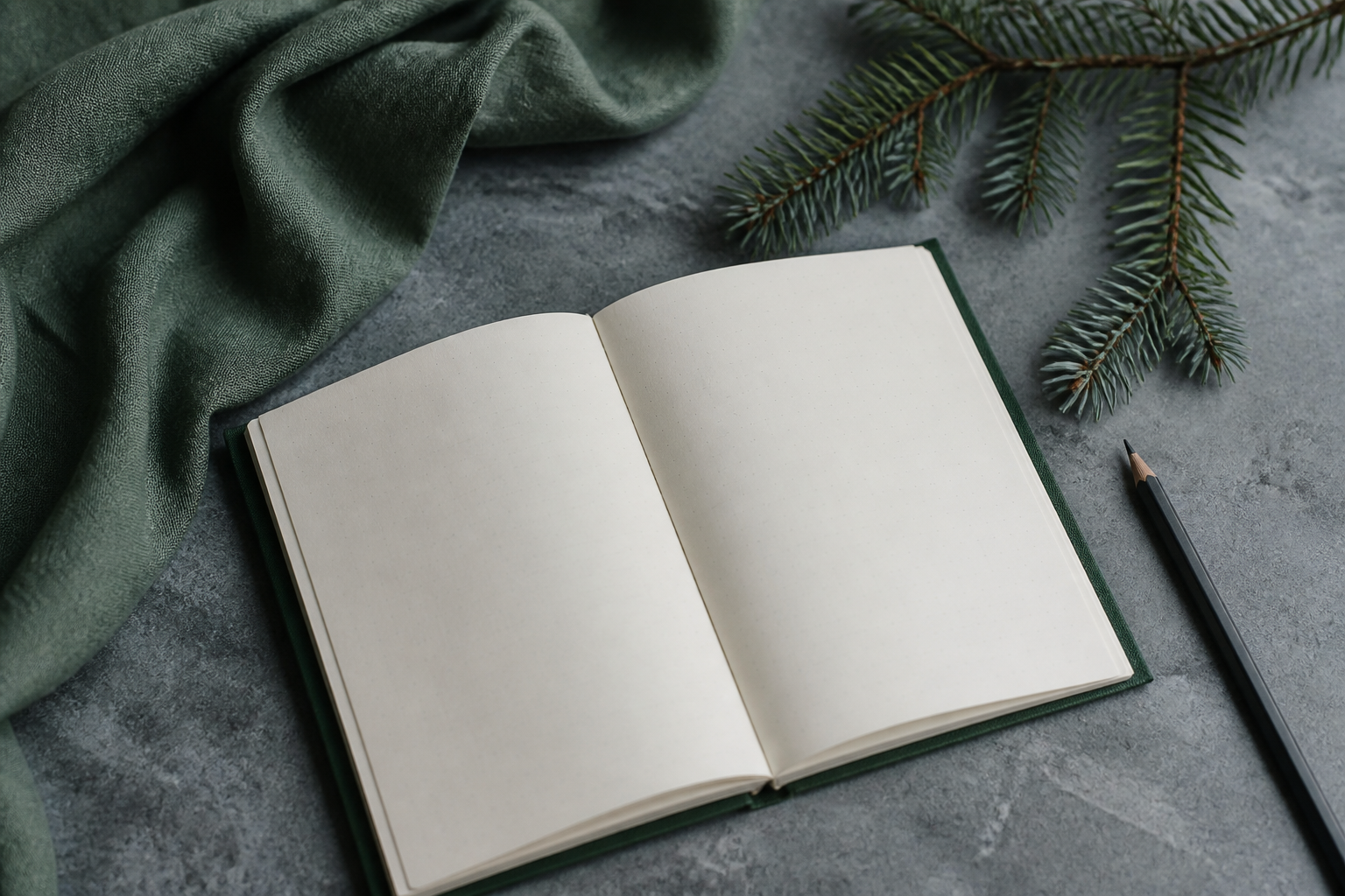 An open cloth notebook on a cool stone table with a spruce sprig