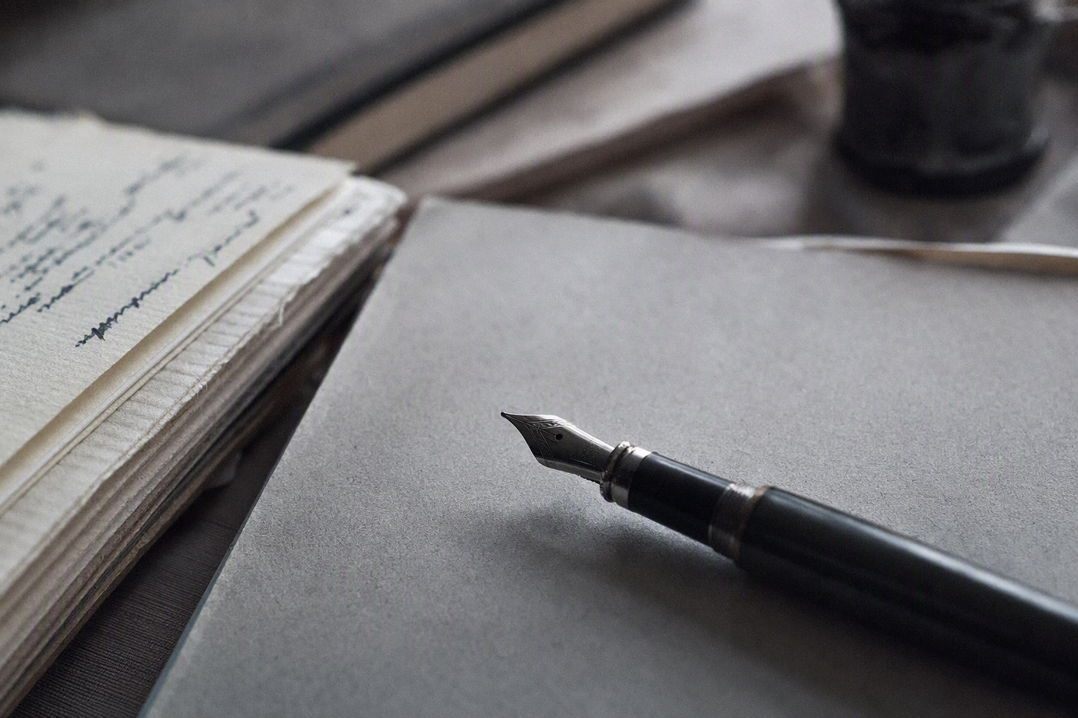 Fountain pen resting on cool grey notebook paper