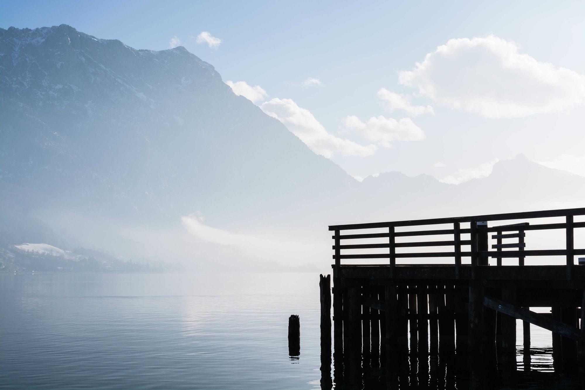 A wooden pier stretching into calm water under a pale sky